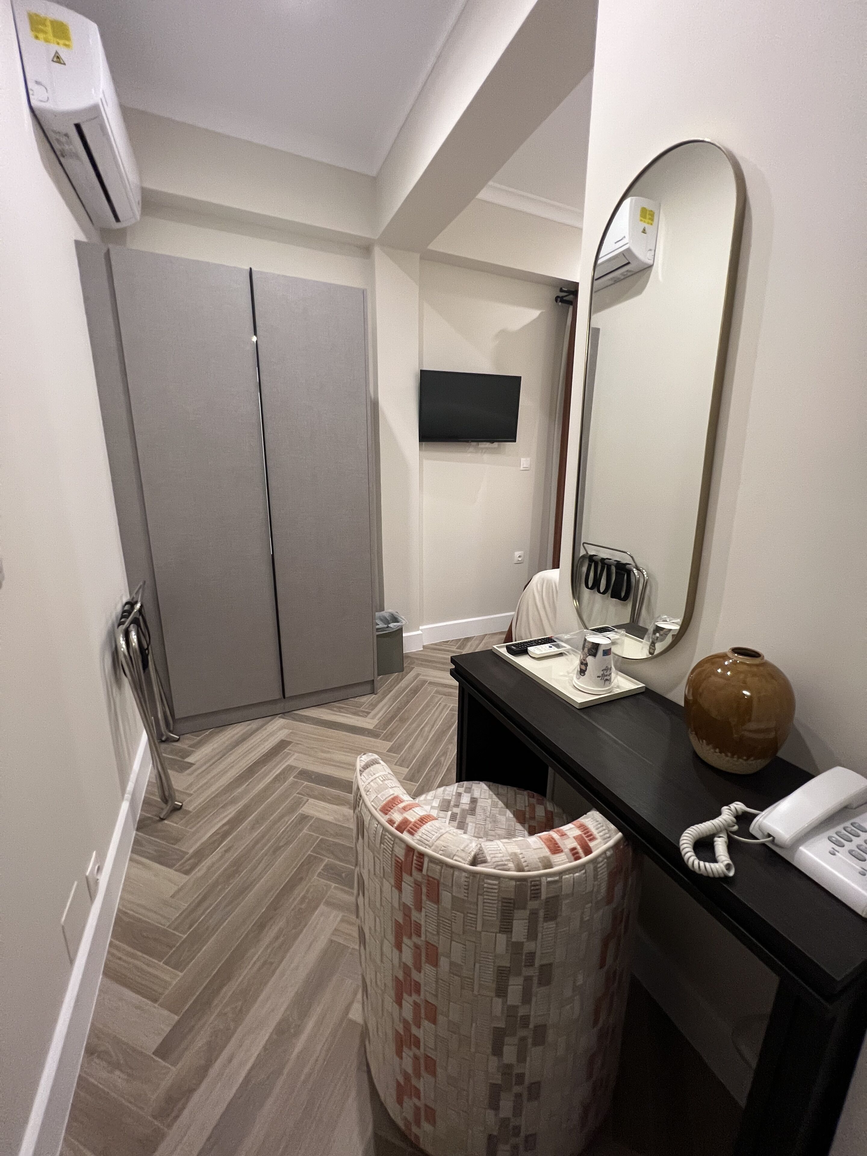 A bathroom with a toilet, sink, mirror, and a small trash bin.