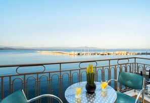 Un balcon avec une table, des chaises et une vue sur la mer et une jetée.