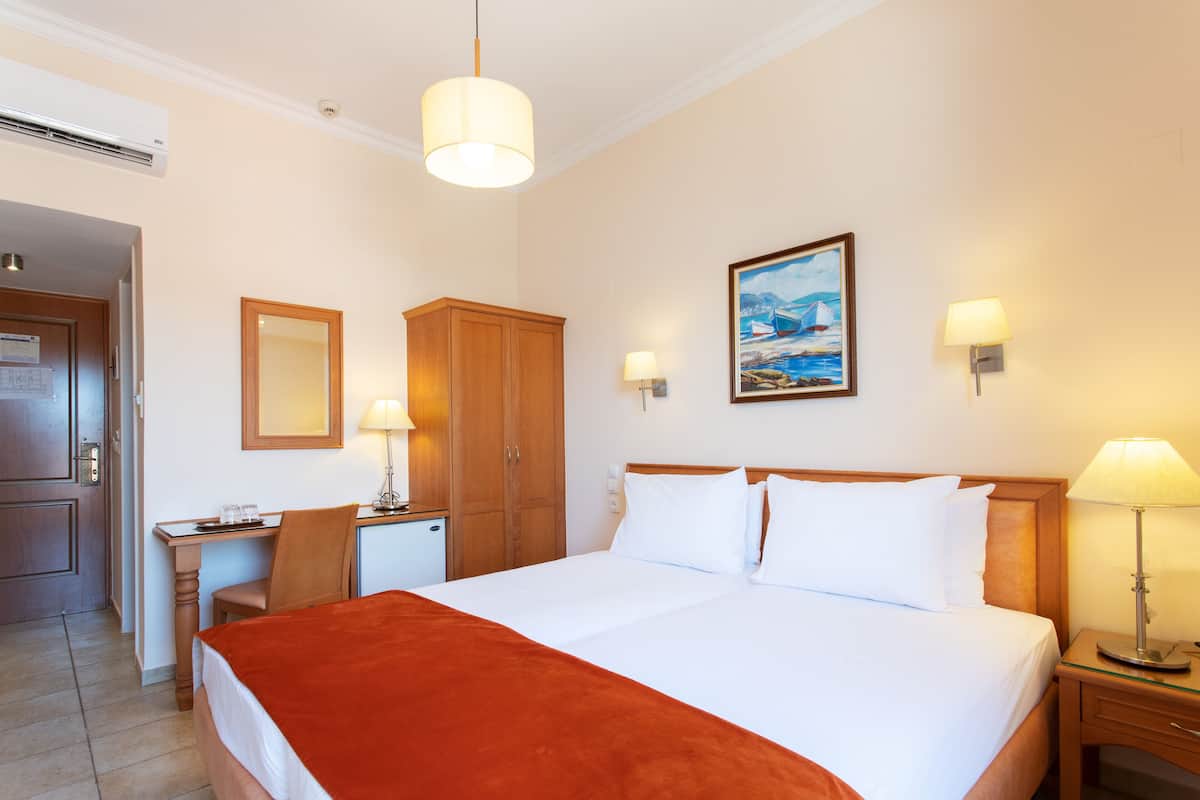 Habitació d'hotel amb llit, escriptori, cadira i un quadre a la paret.