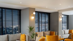 Uma área de estar moderna com um sofá, poltronas amarelas e uma mesa de centro.