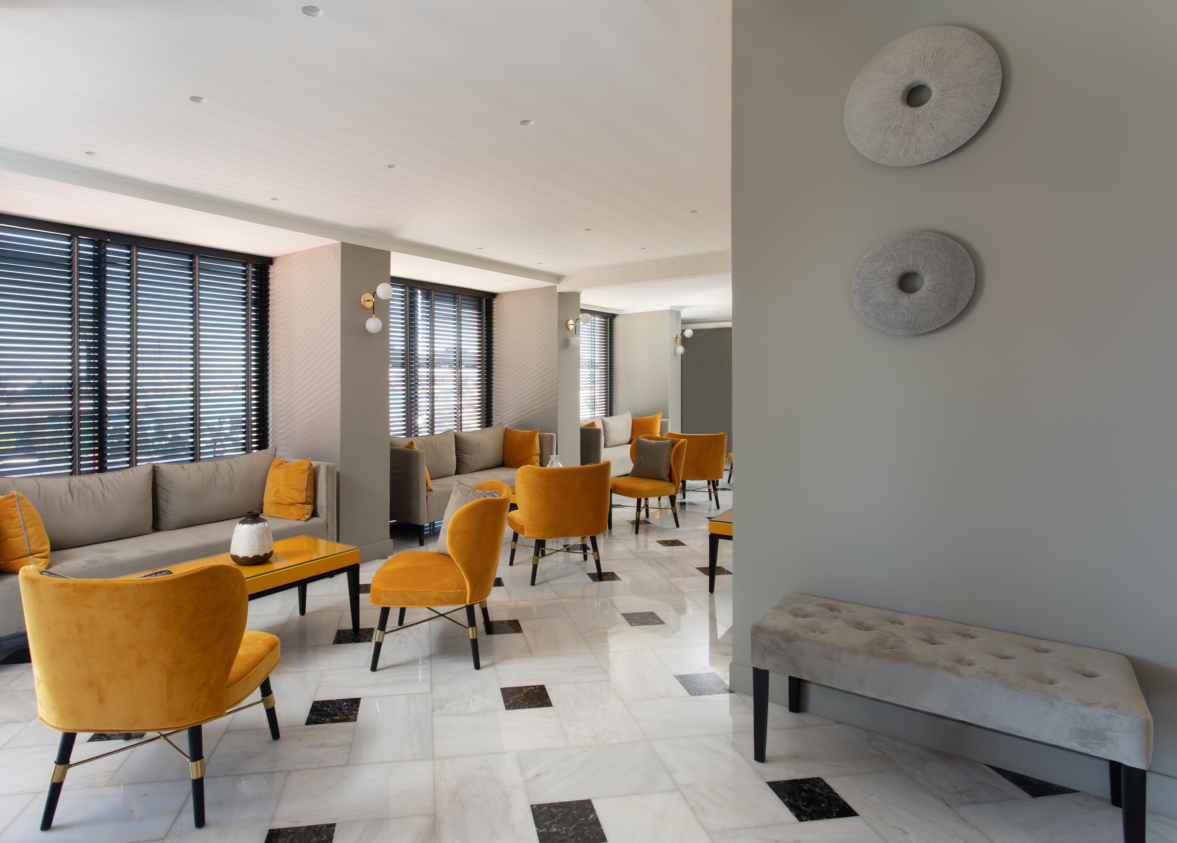 Un moderno vestíbulo de hotel con un sofá, sillas, un banco y un piso con diseño.