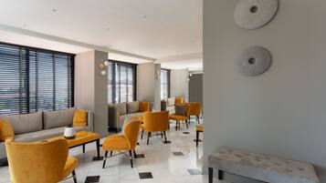 Un moderno vestíbulo de hotel con un sofá, sillas, un banco y un piso con diseño.