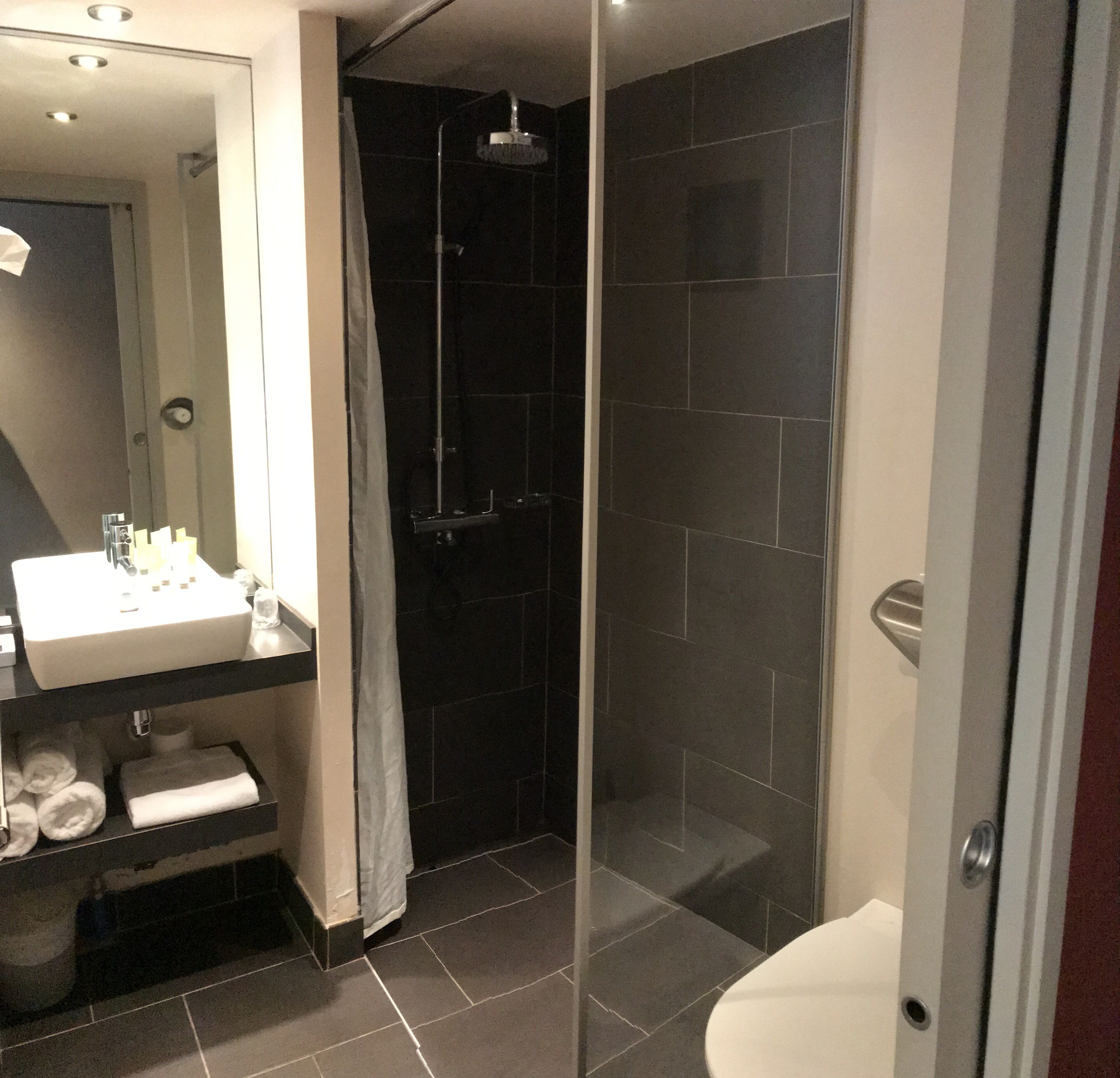 A modern bathroom with a glass-enclosed shower, a white sink, and a mirror.