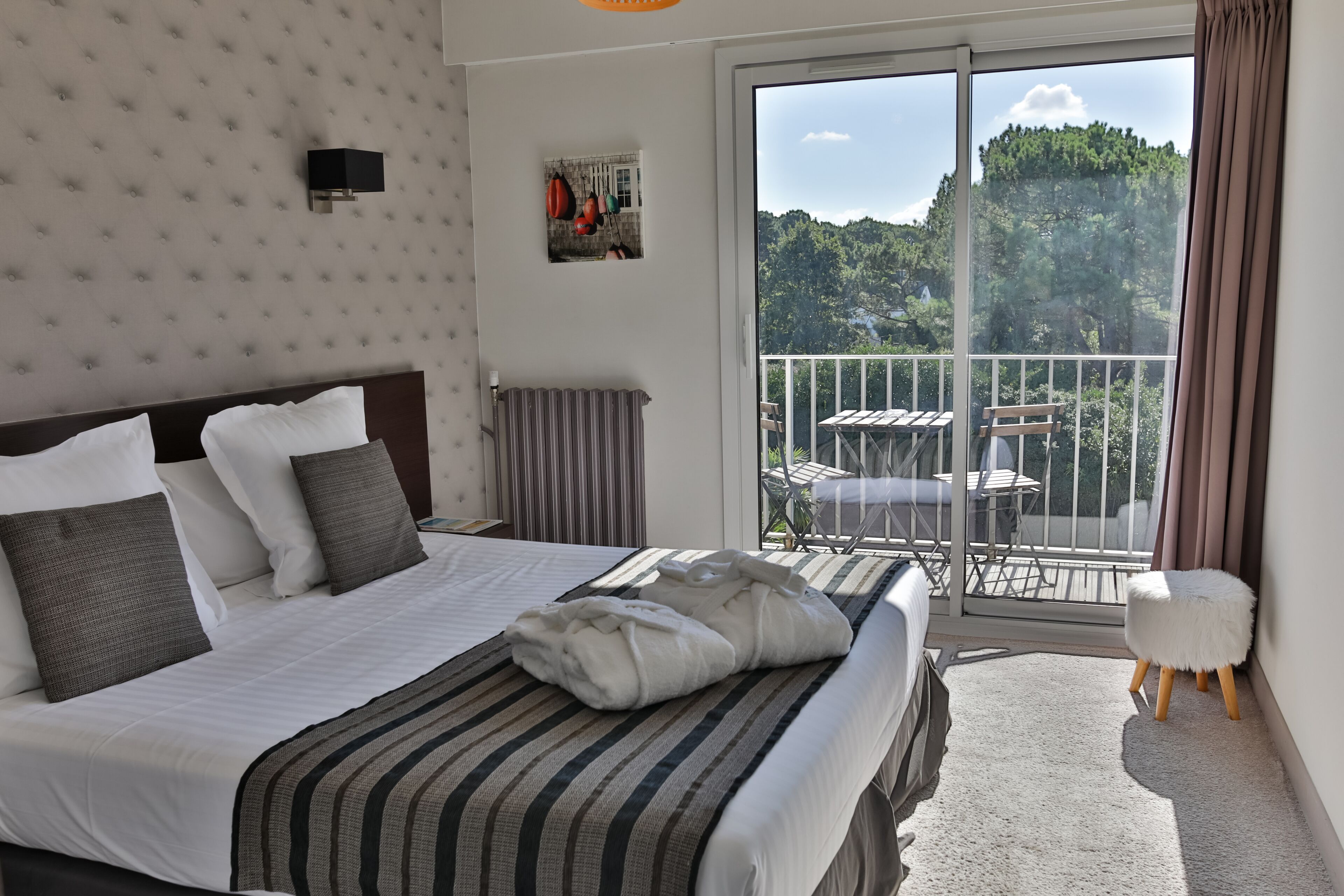 Una habitación de hotel con una cama, vistas al balcón y una pequeña mesa con sillas afuera.