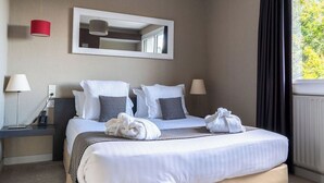 Una habitación de hotel con cama, dos lámparas de noche, un espejo y una ventana con cortinas.