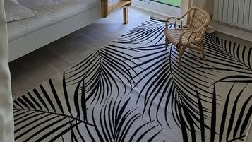 A room with a bunk bed, a wicker ceiling light, a view of a garden through a sliding door, and a zebra-patterned rug.