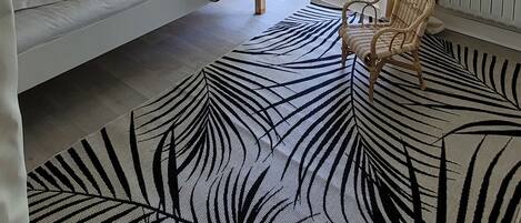 A room with a bunk bed, a wicker ceiling light, a view of a garden through a sliding door, and a zebra-patterned rug.