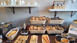Un bufé con diversas opciones de comida, incluyendo pan, bollería y salsas.