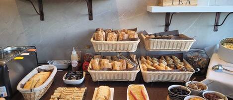 En buffet med forskellige retter, blandt andet brød, kager og tilbehør.
