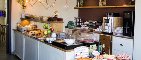 A buffet setup with various food items, a coffee machine, and decorative heart-shaped lights.