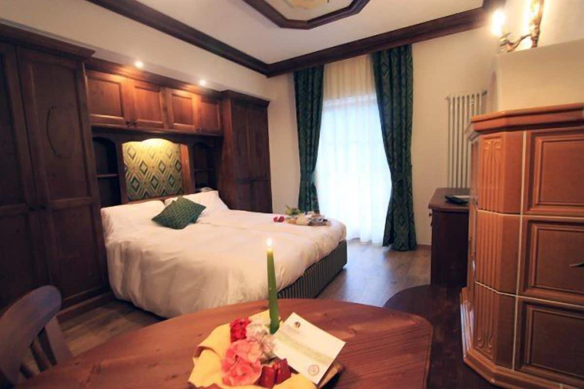Een hotelkamer met een bed, een houten bureau met een kaars en een grote houten kast.