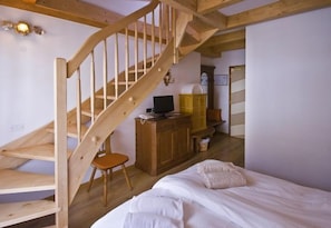 Un dormitorio con escalera de madera, una cama, un escritorio y una silla.