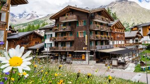 A multi-story wooden hotel with balconies, a restaurant, and outdoor seating. - Hotel Tenne (Saas-Fee)