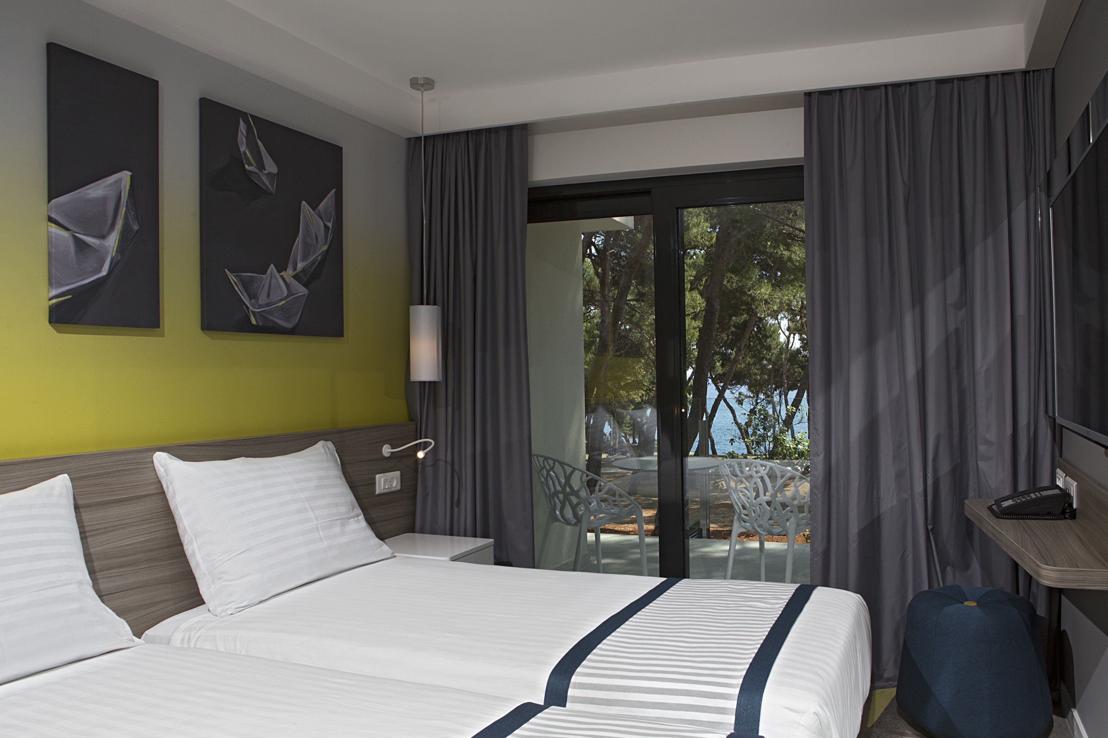 A hotel room with a bed, a desk, a chair, and a view of the outdoors.