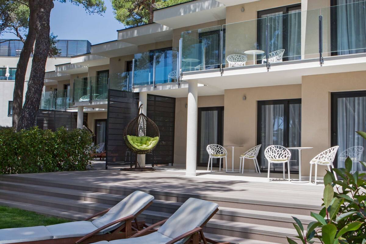 Um hotel moderno com área de piscina, espaço para sentar ao ar livre e varanda com guarda-corpo de vidro.