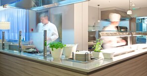 Una cocina moderna con electrodomésticos de acero inoxidable, encimera de vidrio y plantas en macetas.
