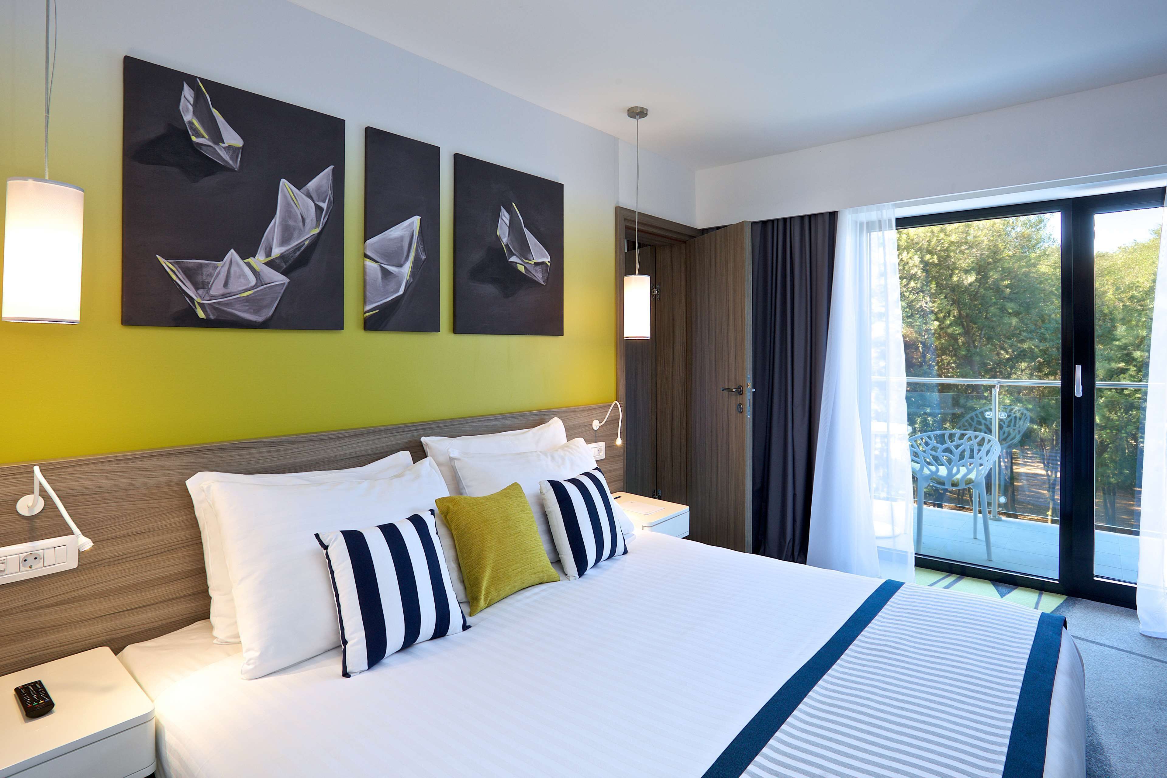A hotel room with a large bed, a bedside table with a phone, and artwork on the wall.