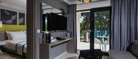 Una habitación de hotel moderna con una cama, un escritorio con televisor de pantalla plana, un sofá y un balcón con puerta de vidrio.