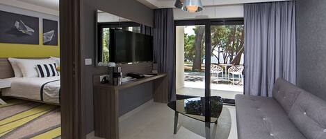 Une chambre d’hôtel moderne équipée d’un canapé, d’une télévision, d’une machine à café et d’un balcon avec mobilier d’extérieur.