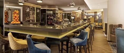Un espace bar moderne doté d’un long comptoir, de nombreux tabourets et d’une grande variété de bouteilles et de verres.