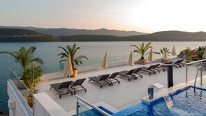 A rooftop pool area with lounge chairs, umbrellas, and a view of the sea and mountains. - Villa Nova (Neum)