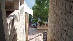 A staircase leading to a balcony with a checkered floor, stone walls, and a view of greenery. - Villa Nova (Neum)