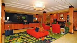Un vestíbulo de hotel con una recepción, un sofá rojo y una alfombra colorida.
