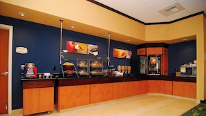Una mesa de buffet con diferentes alimentos y un refrigerador.