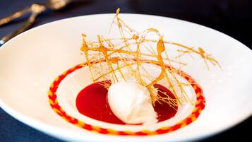 Ein Dessert mit einer weißen Eiskugel in roter Soße, verziert mit goldenen Fäden.