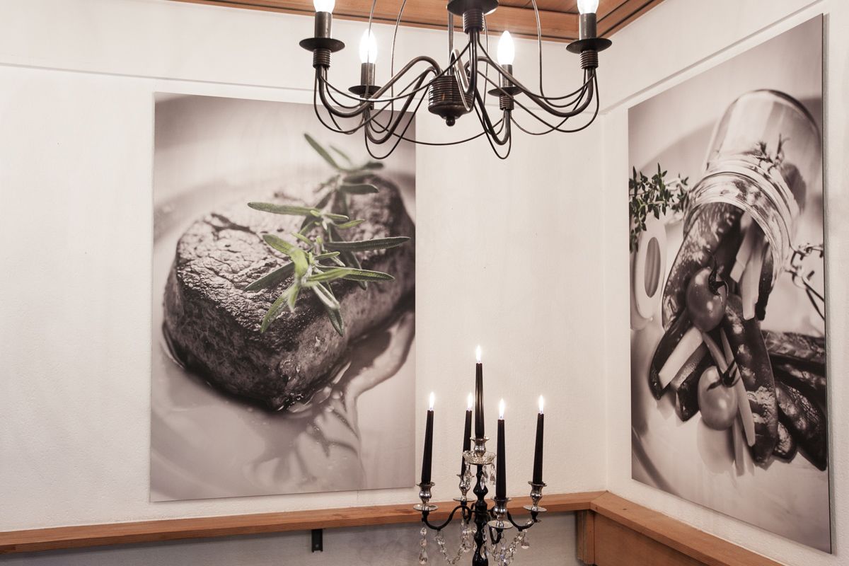 Ein Zimmer mit einer Chandelier, einem Kerzenleuchter und zwei gerahmten Kunstwerken an der Wand.