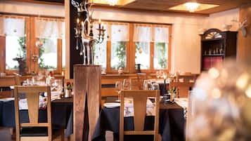 Un restaurante con mesas y sillas de madera, velas y una araña.