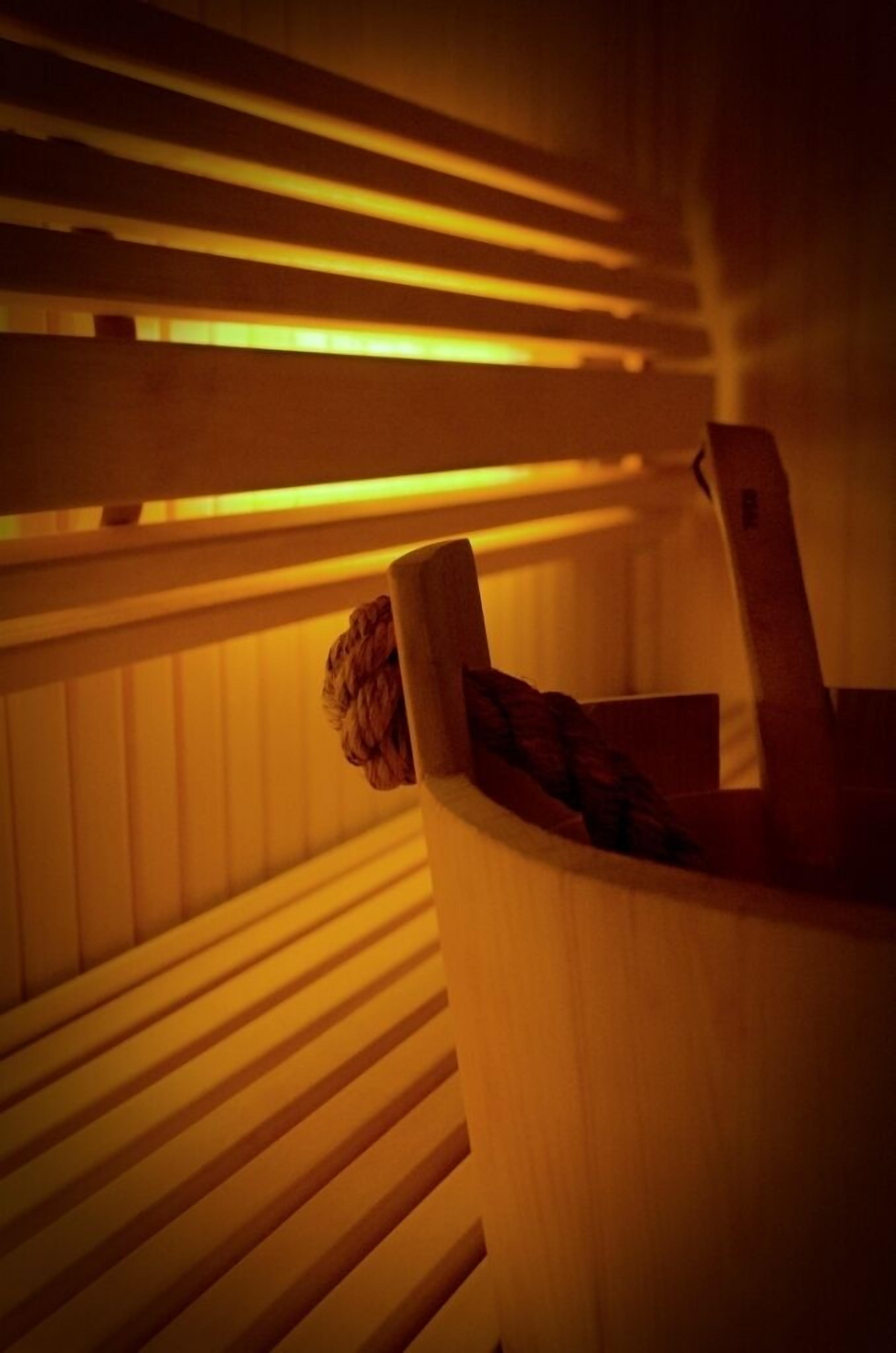 A sauna with wooden benches and a wooden container with a towel.