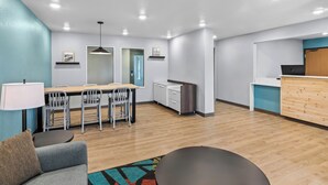 Une pièce moderne et bien éclairée, comprenant un coin repas, un canapé et un comptoir d’accueil.