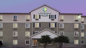 Un hôtel à plusieurs étages, sur lequel on peut lire l’inscription « Woodspring Suites ».