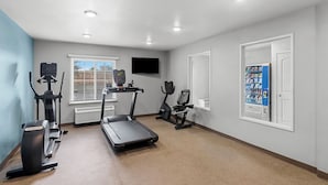 Une salle de sport équipée de tapis de course, de vélos elliptiques et d’un vélo d’appartement.