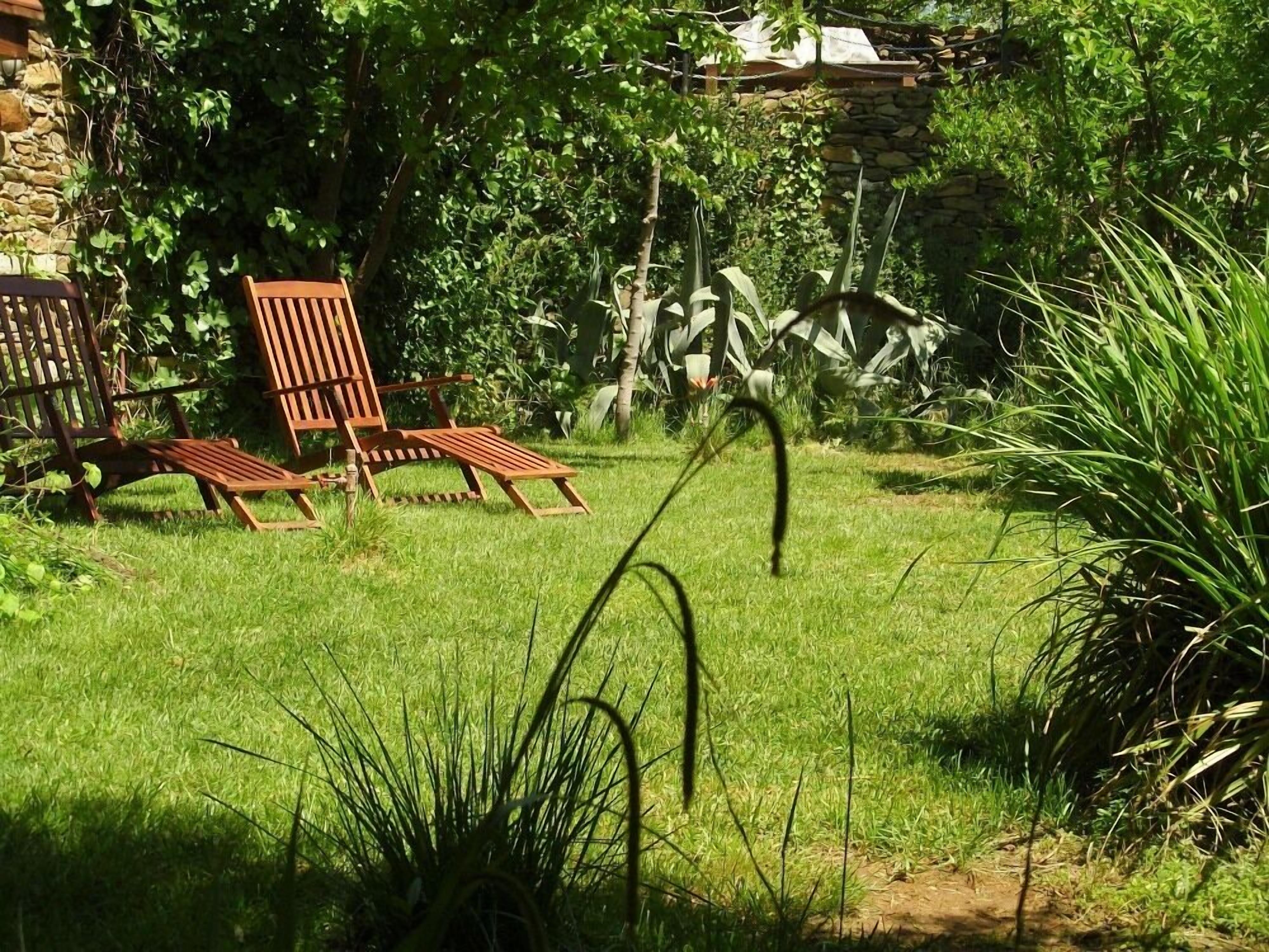 Un jardin avec une chaise en bois et un mur de pierre.