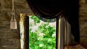A bedroom with a bed, a chair, a window with curtains, and a hanging light fixture. - Terrace Houses Sirince - Fig, Olive Clockmakers and Grapevine (Selçuk)