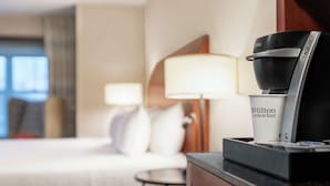 Une chambre d’hôtel avec un lit, une table de chevet équipée d’une machine à café et une lampe.