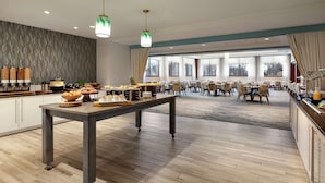 Un grand espace dédié à la salle à manger, comprenant un buffet, plusieurs tables et des chaises.