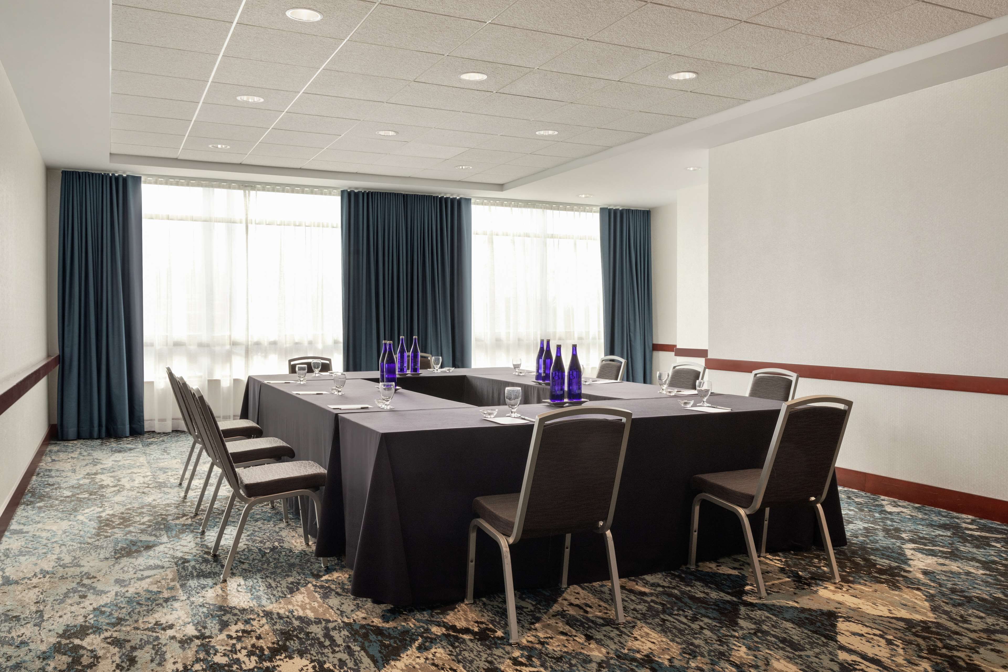 Una sala de conferencias con una larga mesa, sillas y botellas azules sobre la mesa.