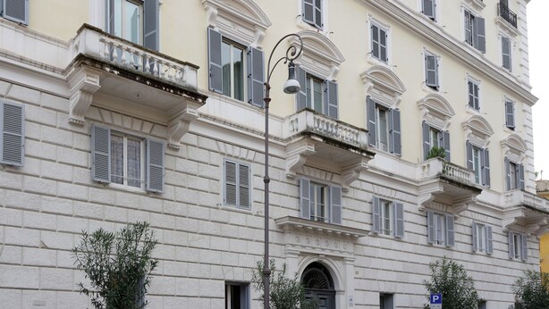 Un edificio de varios pisos con arquitectura clásica, con balcones, ventanas amplias y una farola.