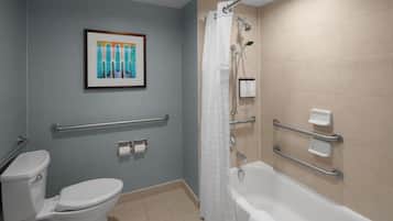 Un baño con inodoro, ducha y barras de apoyo.