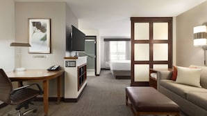 A hotel room with a desk, chair, bed, and a sofa.