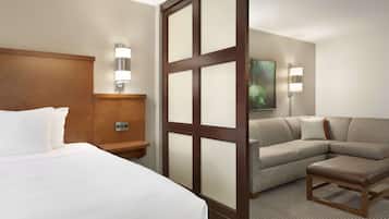 Une chambre d’hôtel avec un grand lit, une tête de lit en bois, un canapé, une petite table et deux lampes fixées au mur.