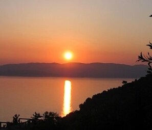 A sunset over a calm body of water with distant mountains. - Selenunda (Skopelos)