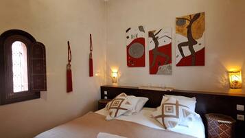Quarto de hotel com uma cama grande, janela com vista e três obras de arte penduradas na parede.