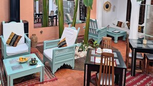 A cozy courtyard with a dining area, seating, and a large plant. - Riad Dar El Grably (Marrakech)
