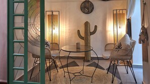 A cozy room with a green spiral staircase, a cactus centerpiece, and two round mirrors on the wall. - Riad Dar El Grably (Marrakech)