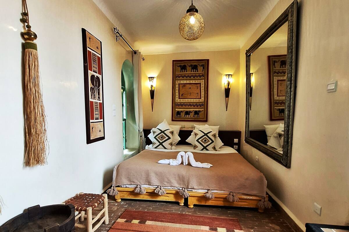Un dormitorio con cama, espejo, luces empotradas y una lámpara colgante.