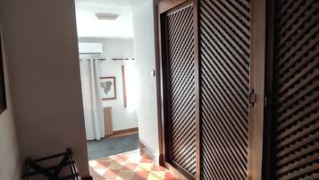 Un pasillo con piso de baldosas, una puerta de madera con diseño de listones y un cuadro en la pared.